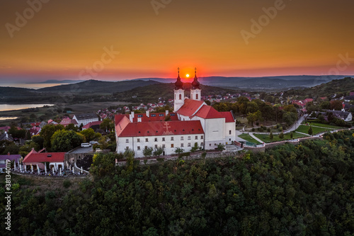 Tihany, Hungary - Aerial skyline view of the famous Benedictine Monastery of Tihany (Tihany Abbey, Tihanyi Apatsag) with beautiful golden sky at sunset over Lake Balaton on a summer afternoon © zgphotography