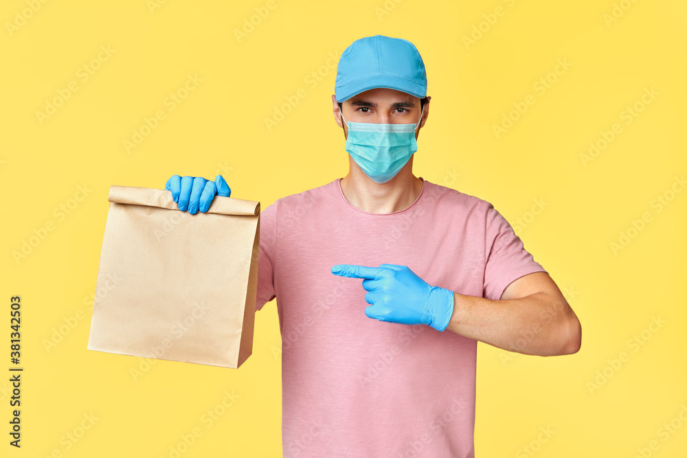 Delivery man pointing on paper packet with food wearing face mask and gloves