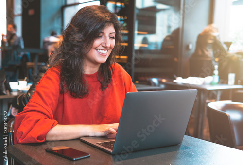 Young woman using laptop in a cafe - remote working concept.