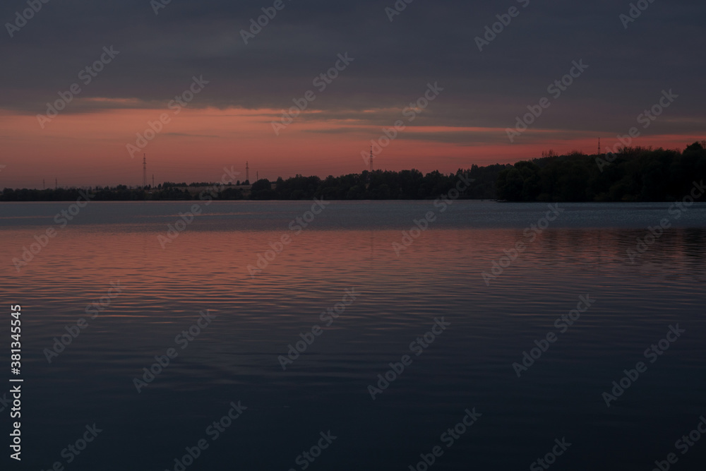 The landscape of the lake shore in Russia against the background of pink twilight, sunset. Large reservoir.