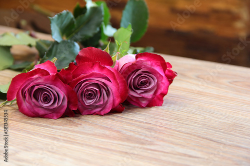 Three pink roses on a wooden background.