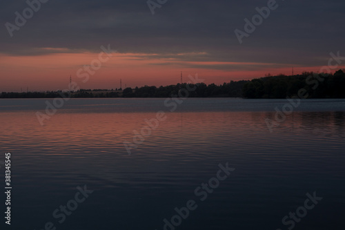 The landscape of the lake shore in Russia against the background of pink twilight  sunset. Large reservoir.