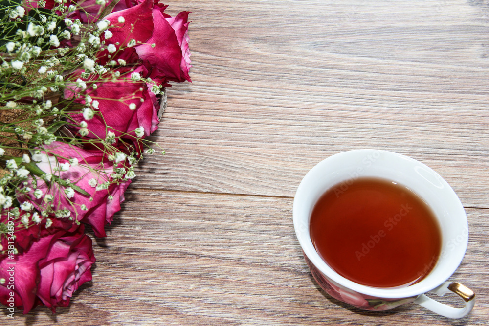 A Cup of tea with roses on a wooden background. A Cup of tea with roses on a wooden background.