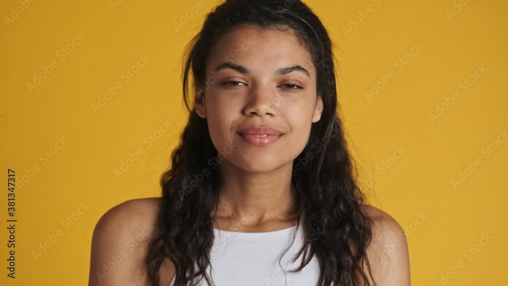 A close-up view of a sleeping young woman is opening her eyes isolated over yellow background A close-up view of a sleeping young woman is opening her eyes isolated over yellow background