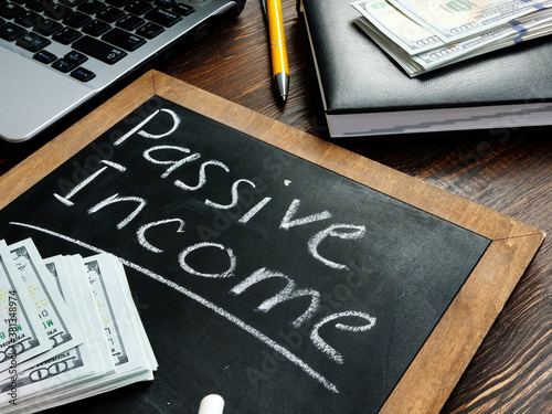 Passive income inscription on the board and a bundle of bills. photo
