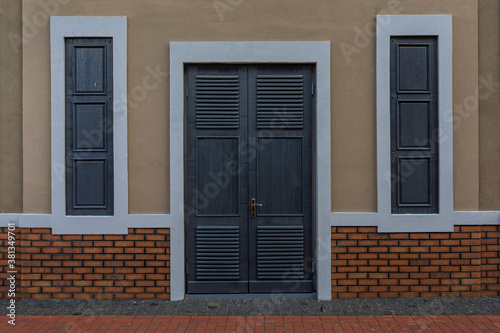 Wall with wooden doors and closed windows.