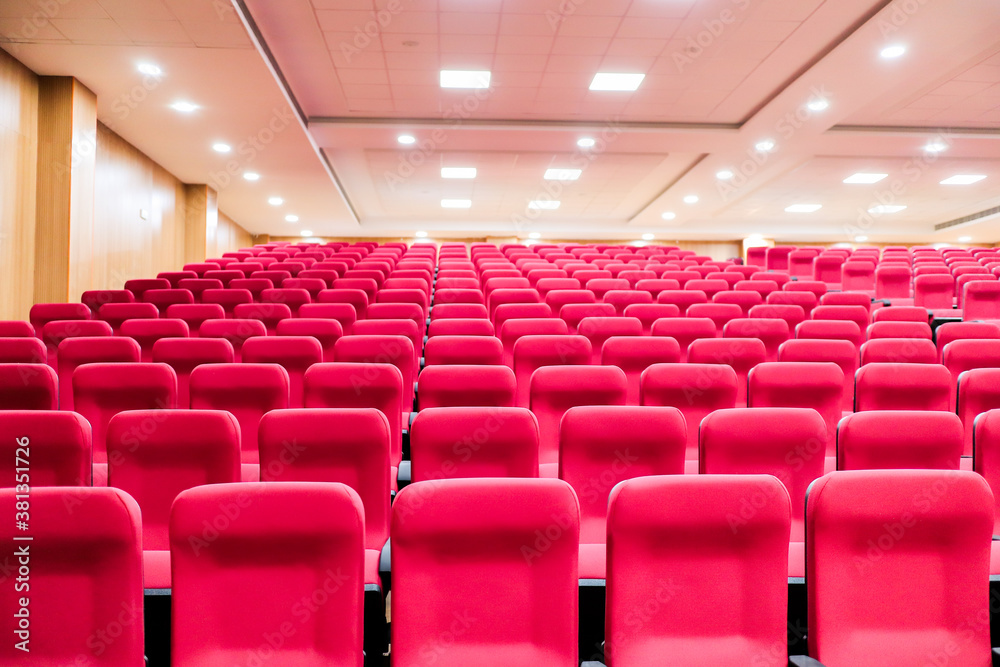 empty seats of an auditorium with red reclining rows of seats and false ceiling led lights empty seats of an auditorium with red reclining rows of seats and false ceiling led lights