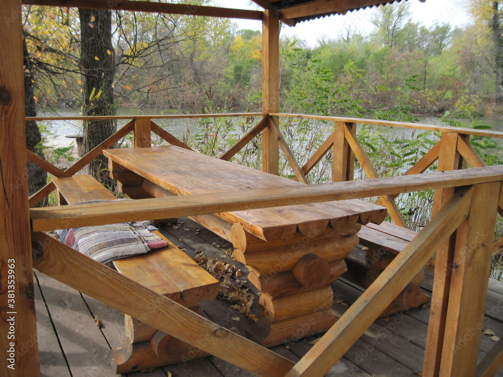 wooden chairs on the beach. Rest time in natural wooden bower on a sunny day in beautiful time of golden autumn. Relax with comfort in wild nature. 
