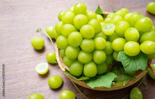 Obraz na płótnie Green grape in Bamboo basket on wooden table in garden, Shine Muscat Grape with