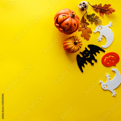Pumpkins with Halloween decorations on yellow background