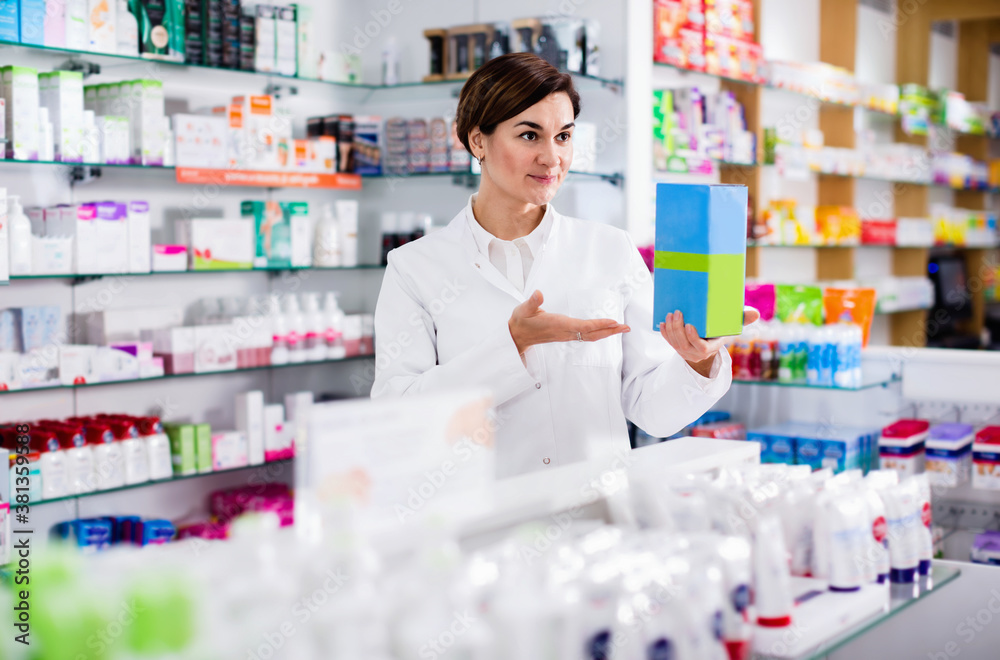 Glad cheerful positive female pharmacist suggesting useful body care products in pharmacy