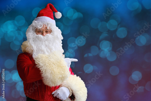 adult santa claus with white beard on a beautiful blue background shows his finger to the side, concept of christmas, waiting for gifts, sales and discounts, festive mood