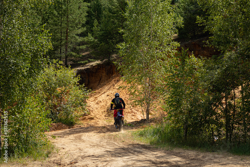 Outfitted biker on off-road motorcycle riding through abandoned sand quarry, extreme hobby. Motocross.