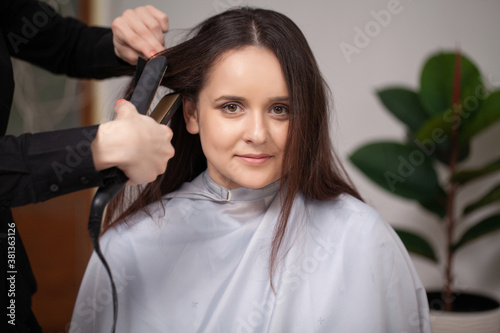 Professional hairdresser working with young woman in beauty salon.