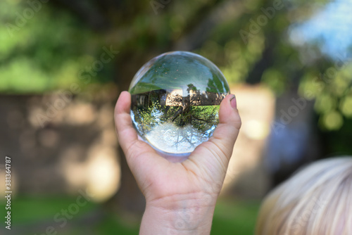 a boy holds a glass ball with reflection of a tree as an environmental conservation concept