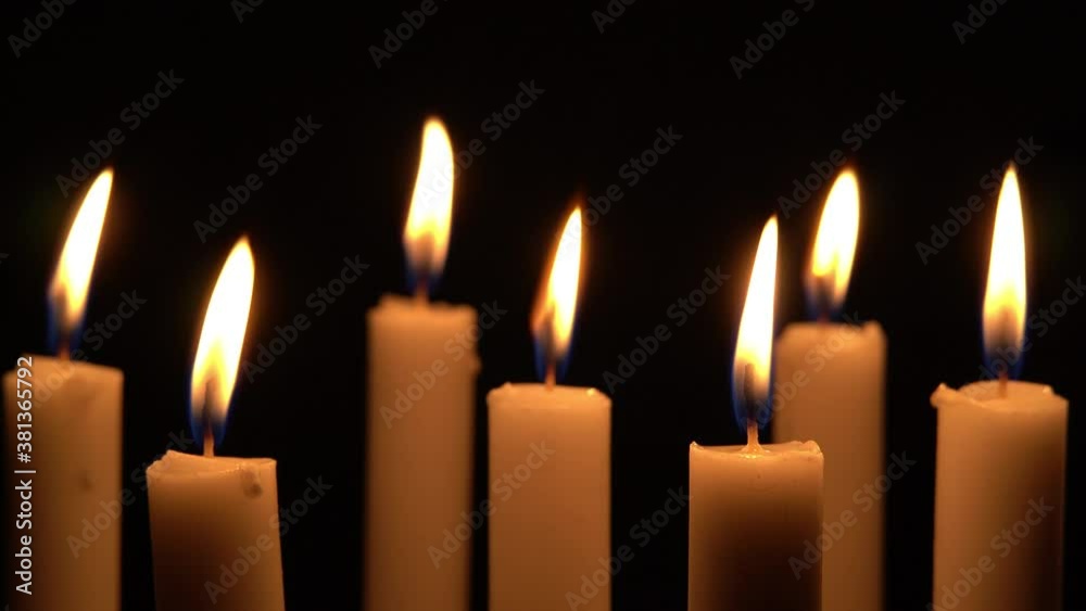 Close up view of candlelight burning in the dark, candles in the dark swayed by the wind breeze. Close up view of candlelight burning in the dark, candles in the dark swayed by the wind breeze.