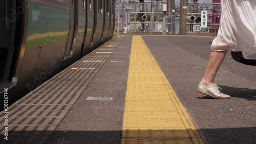 Woman run out from train, slow motion shot of legs jumping to platform, white skirt fly in air. Sunny day, rapid transit train arrive to terminal station at Narita. photo