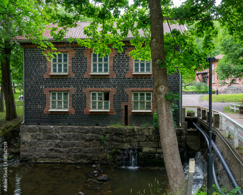 Fiskars village and its mill in the summer time. Former iron works mill built of slag brick (built in 1898). Some trees and a river, Finland. photo