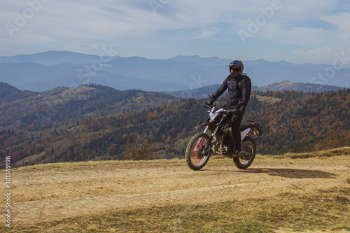 Fototapeta Naklejka Na Ścianę i Meble -  A man in motorcycle protection and helmet riding his motorcycle bike in the highland dusty off-road, mountain biking
