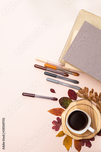 A cup of coffee, autumn leaves, books and colored pens on a light background top view. Cozy home autumn concept