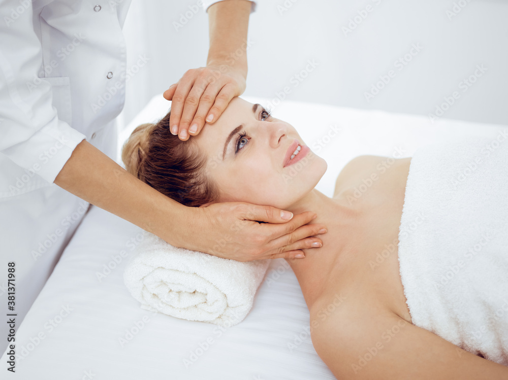 Young and blonde woman enjoying facial massage in spa salon. Beauty concept Young and blonde woman enjoying facial massage in spa salon. Beauty concept