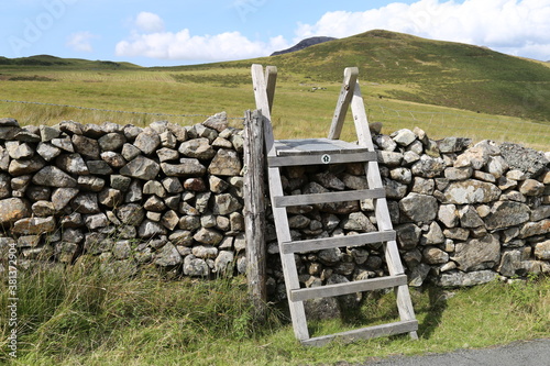 A closeup view of a wooden stile over a dry stone wall in Gwynedd, Wales, UK. 