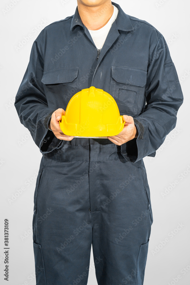 Worker standing in blue coverall holding hardhat Worker standing in blue coverall holding hardhat