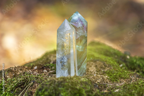 Gemstones fluorite, quartz crystal. Magic rock for mystic ritual, witchcraft Wiccan and spiritual practice on stump in forest. Meditation reiki, spiritual healing consept. Out focus, bakclight photo