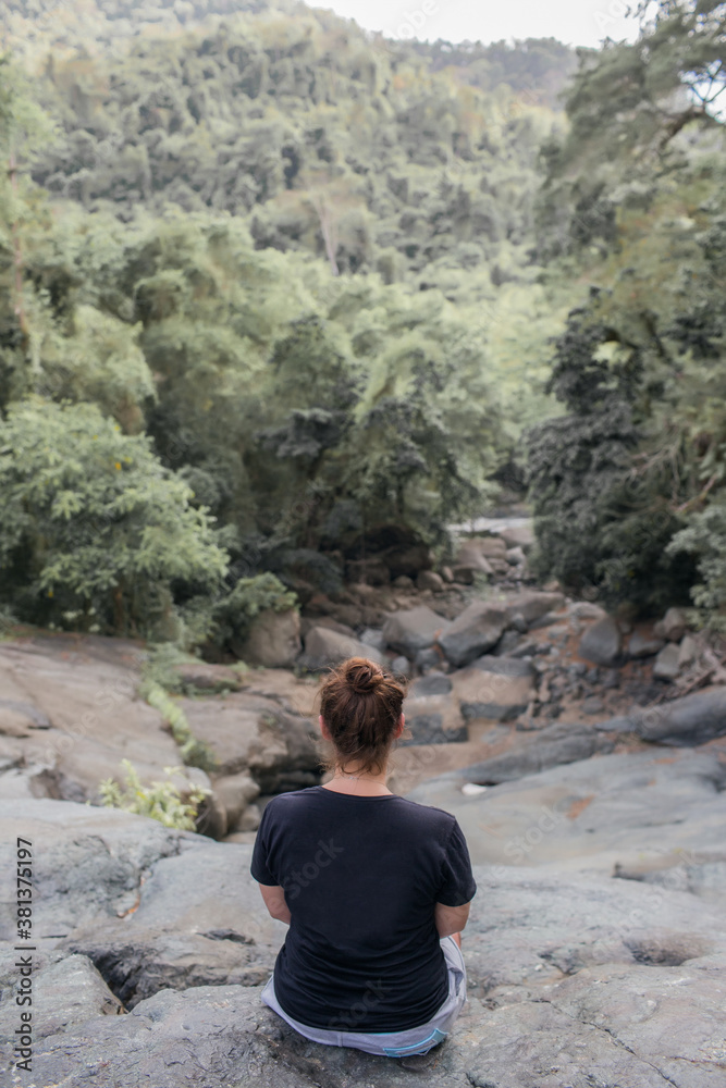 girl sits on a stone in the forest.