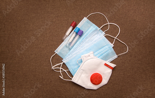 Medical background - medical mask, respirator and test tubes on brown background photo