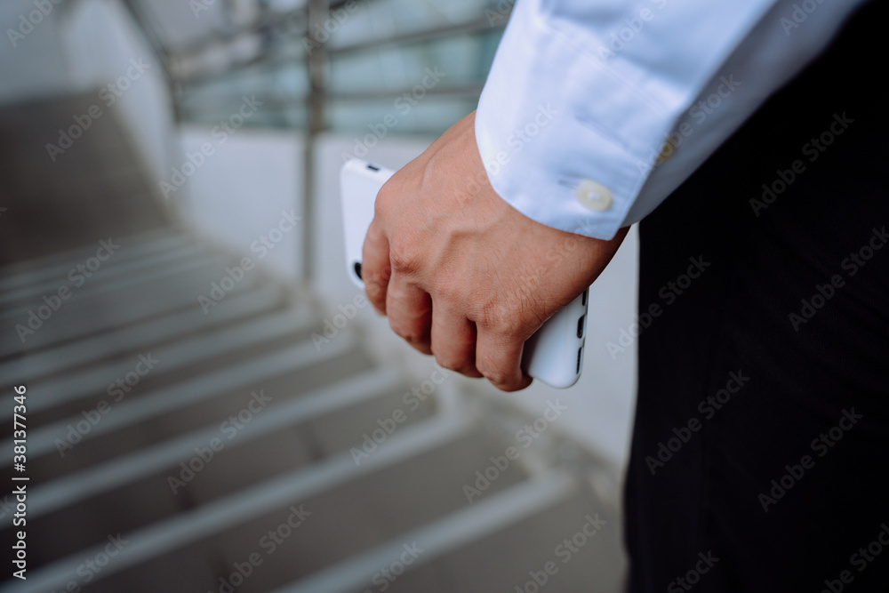 Close up of business man hand holding smartphone in city.