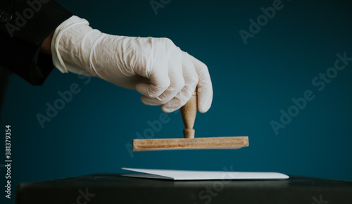 Close-up of voter with protection gloves putting stamp on the voting card during cobid19 pandemics. photo