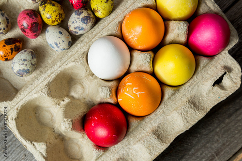 Wall Mural Dyed easter eggs in cardboard box on wooden background.