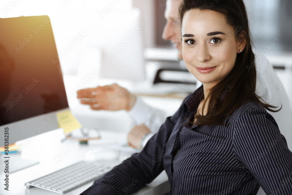 Business woman and man discussing questions while using computer at workplace in sunny office Business woman and man discussing questions while using computer at workplace in sunny office