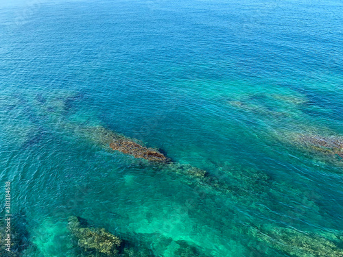 View of a coral reef. Turquoise sea water. Calm ocean. Mediterranean coast. Rocky beach