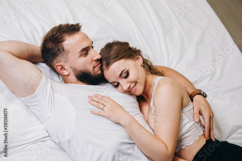 Beautiful couple kissing in bed. Young happy family lying together