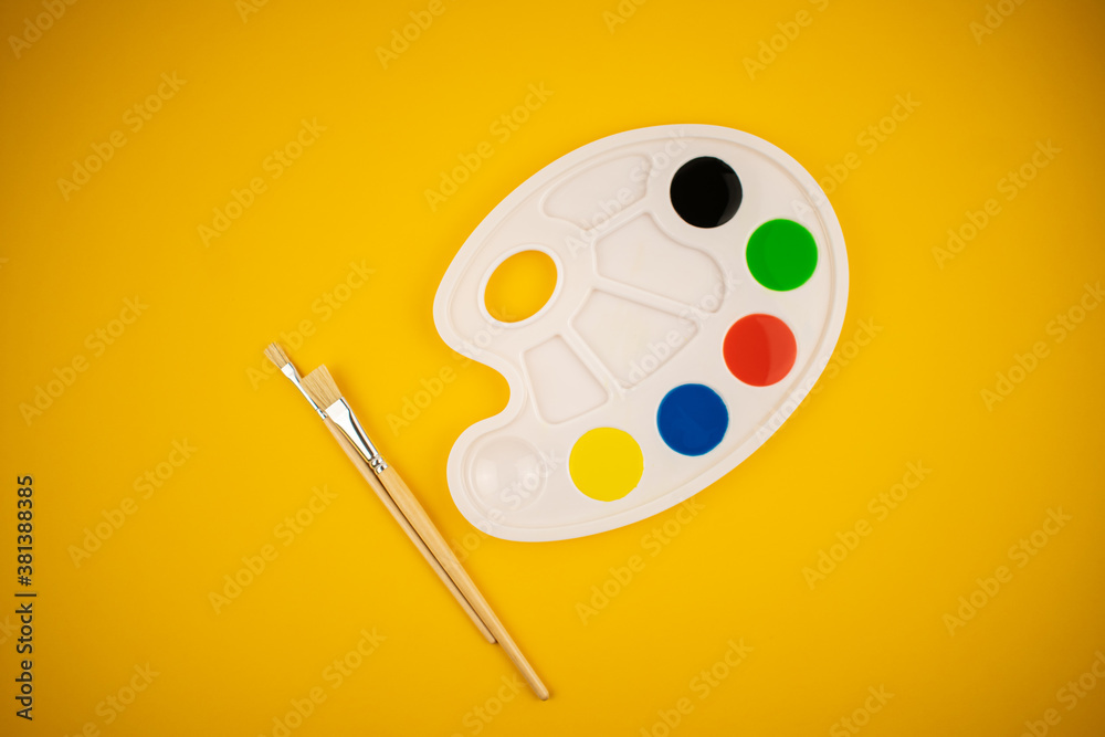 A palette of colors of honey paints with a brush on a yellow background.