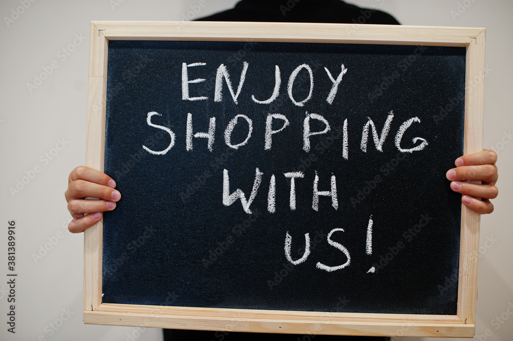 Enjoy shopping with us! written on blackboard. Black friday concept. Boy hold board. Enjoy shopping with us! written on blackboard. Black friday concept. Boy hold board.