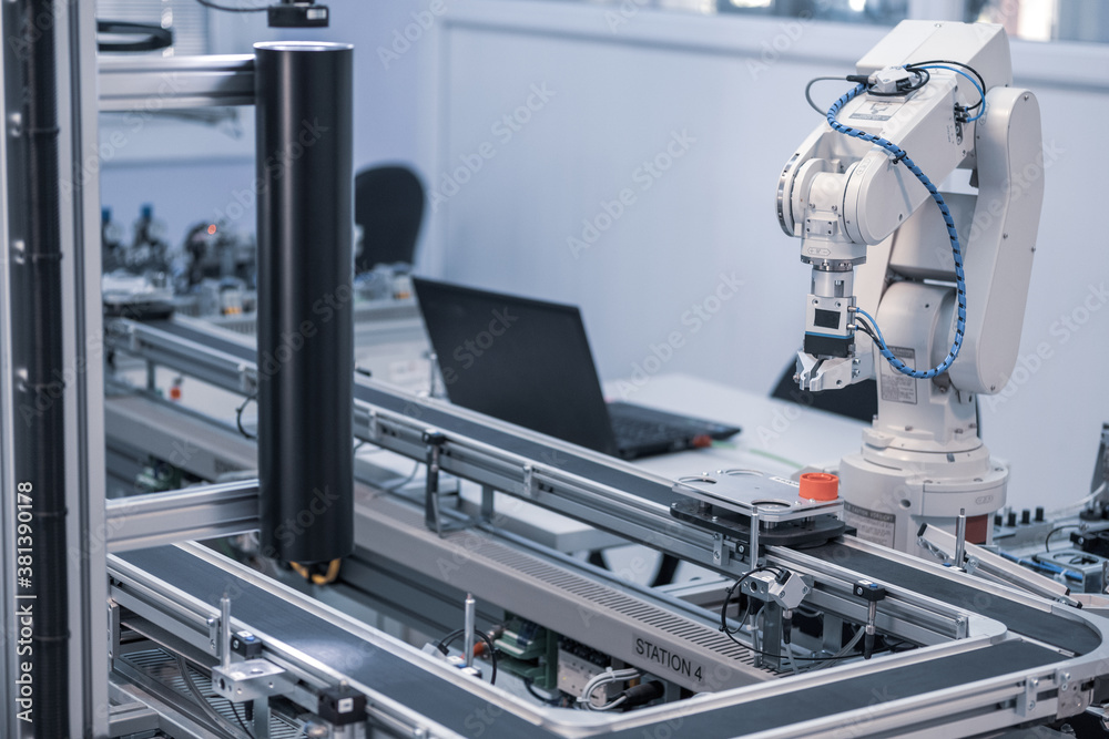 Industry 4.0 concept; artificial intelligence in smart factory prototype. The robot picks up the product from an automated car on the production line. Focus on the robotic arm's gripper.