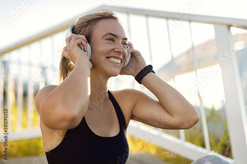 Fototapeta Naklejka Na Ścianę i Meble -  Happy athletic woman listening music over headphones outdoors.