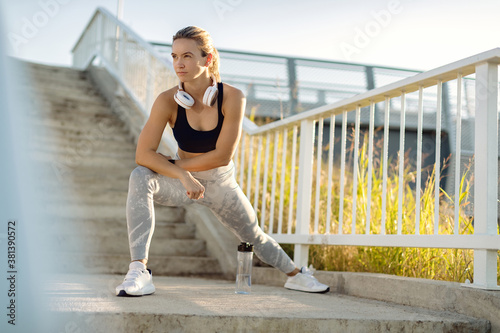 Young sportswoman doing stretching exercises outdoors. © Drazen