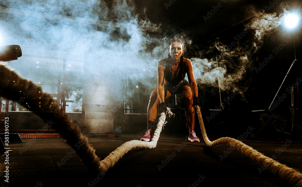 Obraz premium beautiful young black sportswoman in the gym. performs a workout.