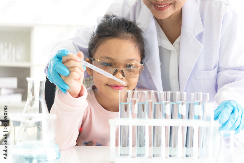 Asian children analyzing study evaluating microscope with scientist. Health care researchers doing some research with dropper chemical testing and working in life science laboratory Asian children analyzing study evaluating microscope with scientist. Health care researchers doing some research with dropper chemical testing and working in life science laboratory
