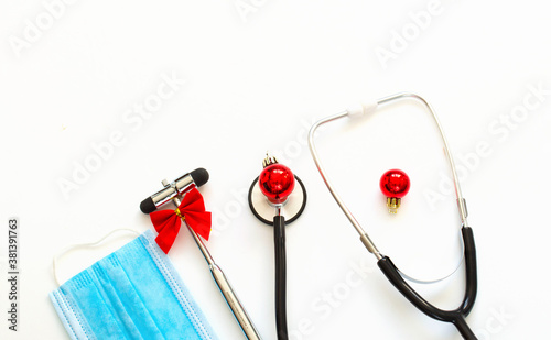 christmas medical flatlay. Medical stethoscope, neurological hammer, gift, Christmas decorations on a white background. Copyspace.