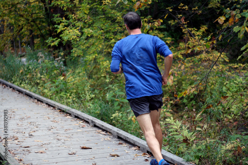 un homme fait son jogging dans un parc boisé photo