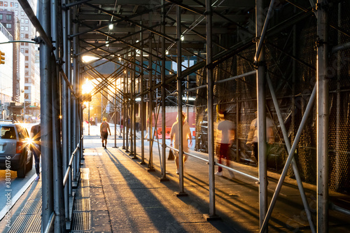 Fotografia People walking under construction scaffolding on the streets of New York City wi