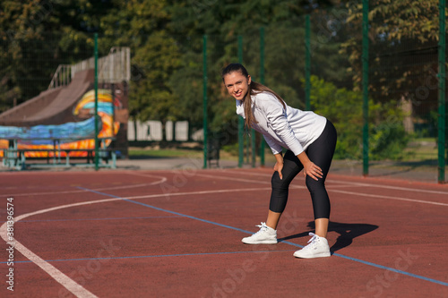 Sporty young girl warming up before training on the playground on a sunny day