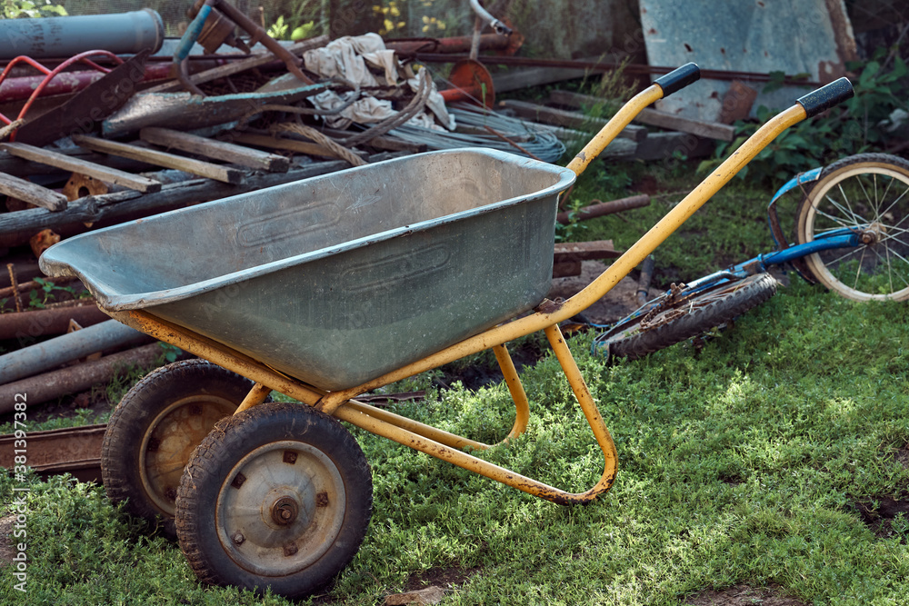 Wheelbarrow near stack of garbage in yard Wheelbarrow near stack of garbage in yard