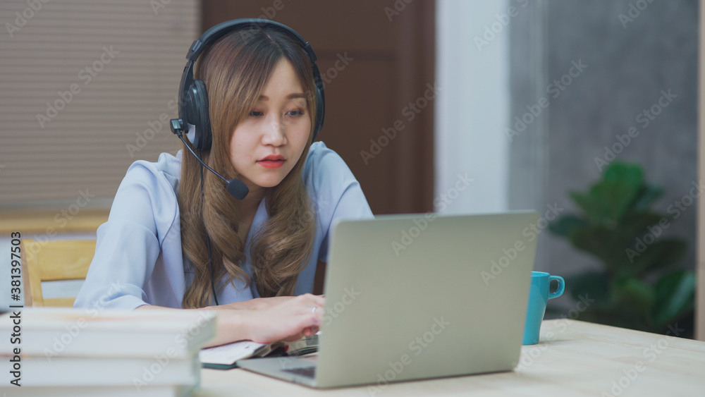 Young Asian woman wear headphone using laptop computer as webcam working and studying online at home, Chinese teenage girl study from internet for new normal distance learning concept Young Asian woman wear headphone using laptop computer as webcam working and studying online at home, Chinese teenage girl study from internet for new normal distance learning concept