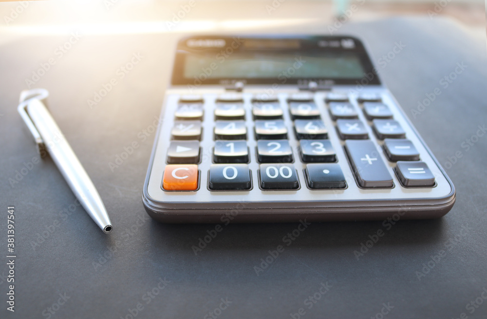 Calculator and a pen arranged on a table to convey the concepts of tax season and monthly expenses (Select focust) Calculator and a pen arranged on a table to convey the concepts of tax season and monthly expenses (Select focust)